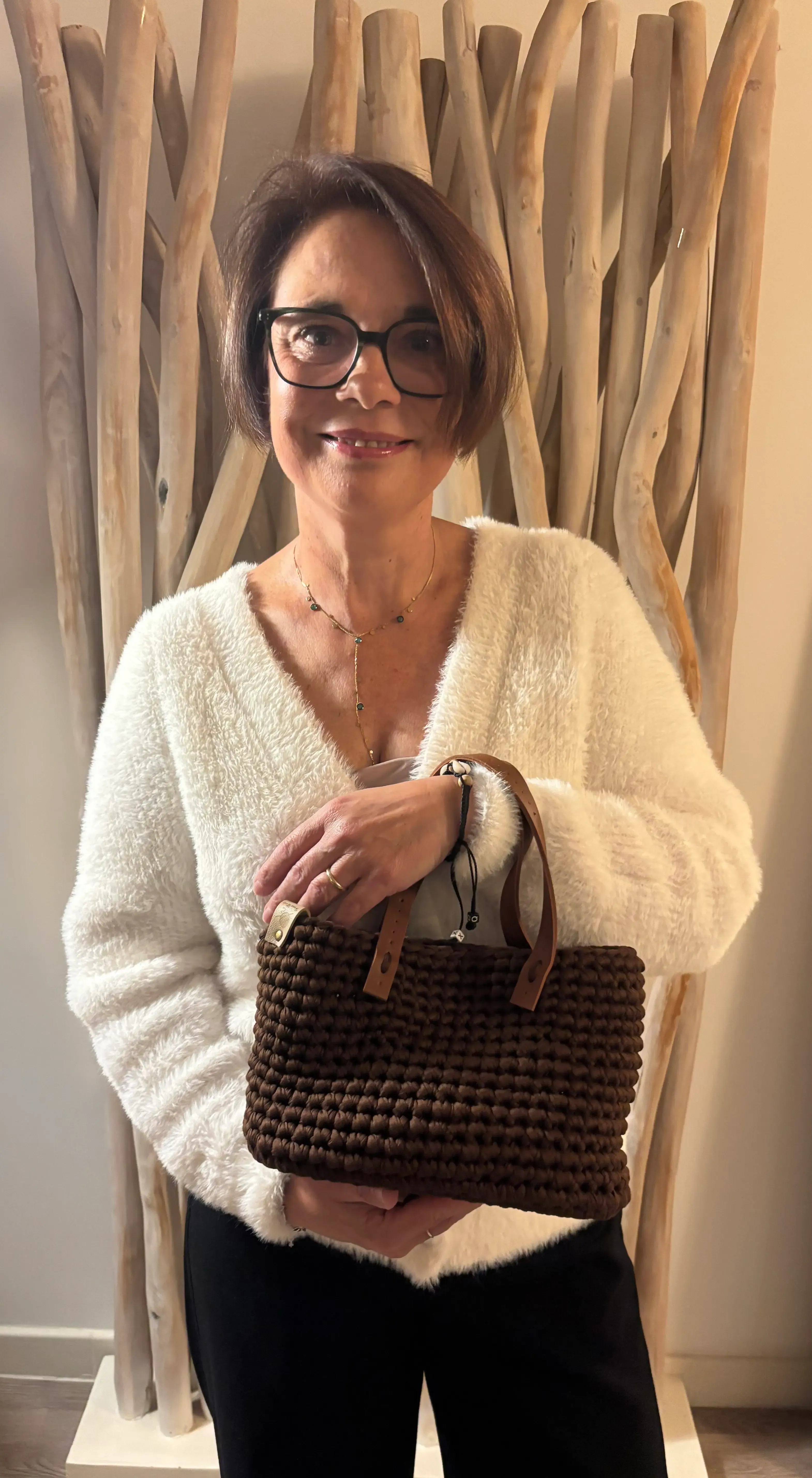 Karina, souriante, un sac Lola chocolat à la main